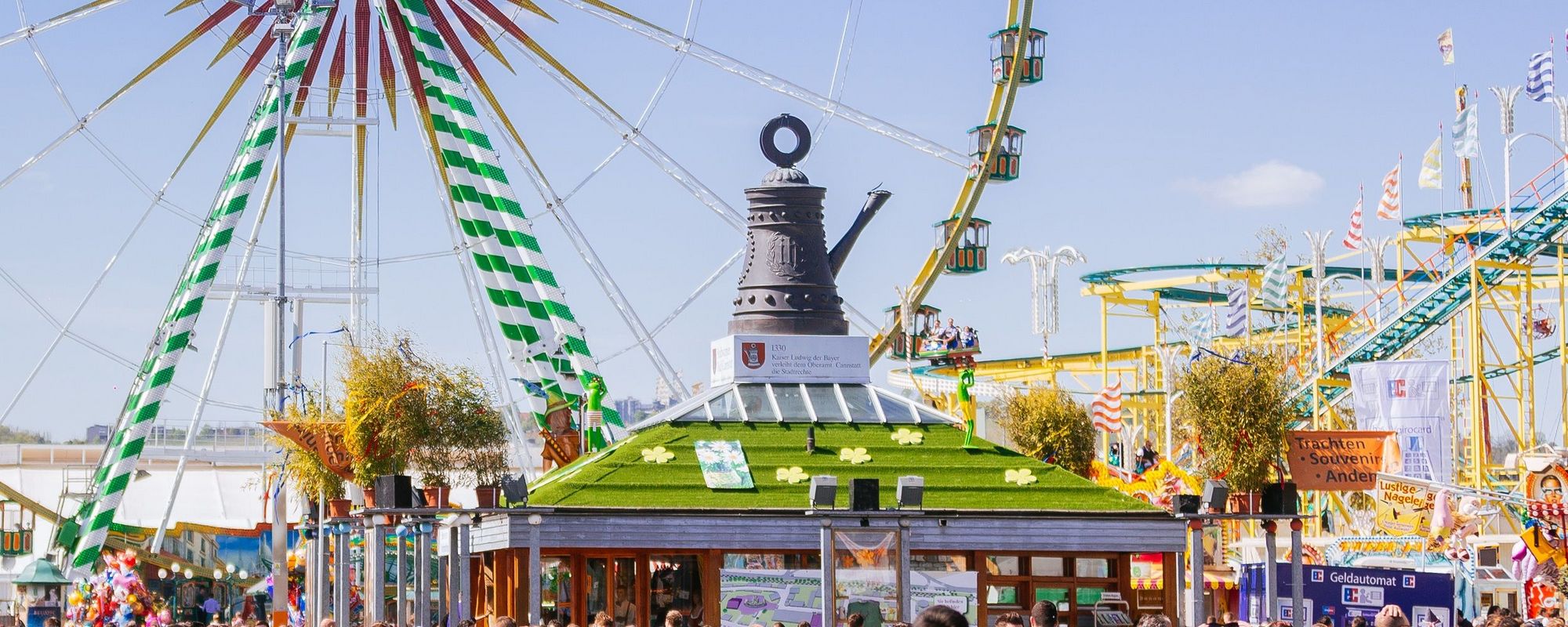 Blick auf die Cannstatter Kanne. Davor tummeln sich die Menschen. Im Hintergrund steht das Riesenrad