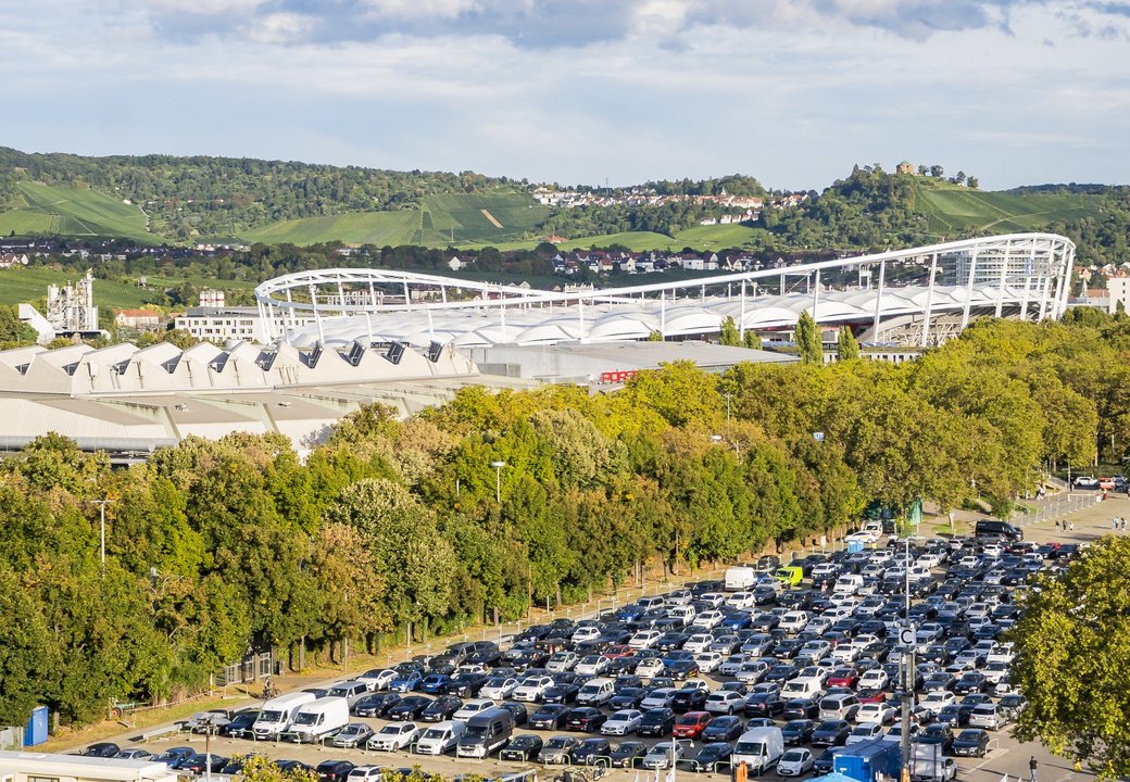 Parkplatz auf dem Wasen aus der Vogelperspektive. Im Hintergrund sieht man die MHP Arena hinter den Baumkronen emporragen